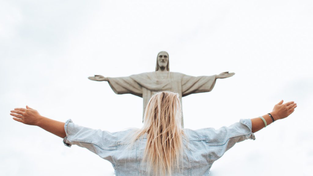 Women standing before a statue of Jesus with outstretched arms