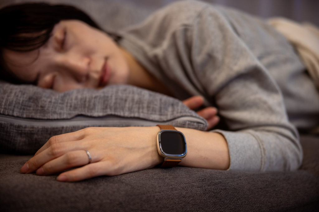 Woman sleeping at home, wearing smartwatch for sleep management to get better sleep