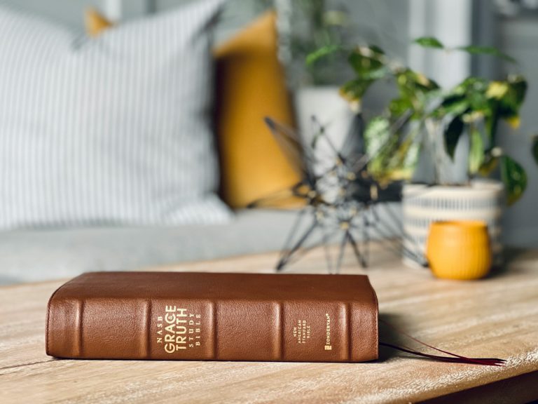 A brown Bible sits on a light wood table holding in its pages essential truth about Jesus.