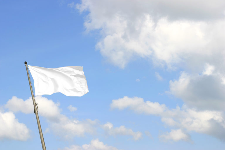 A white flag against a blue sky with clouds reminds you to lay down your fight.