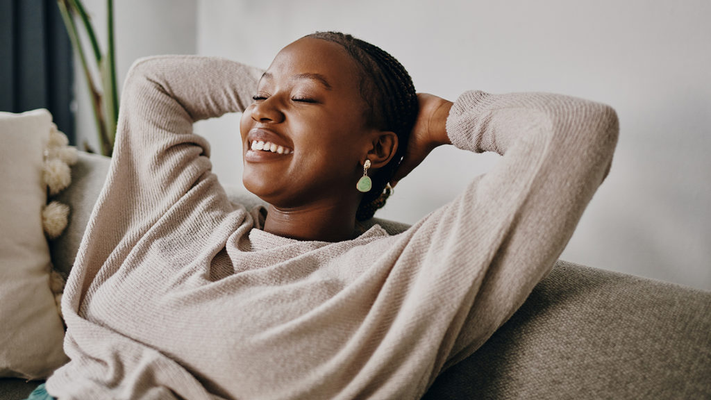 Royalty-Free Stock Photo: Woman relaxing on her sofa after achieving contentment.