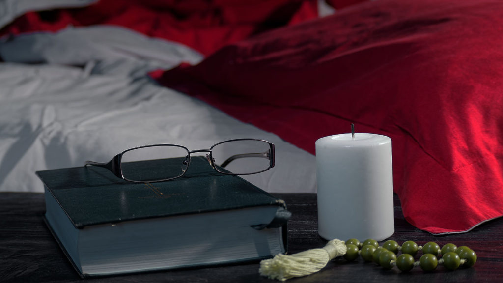 A Bible on a nightstand next to an unlit candle remind you to keep God's Word near when you can't sleep.