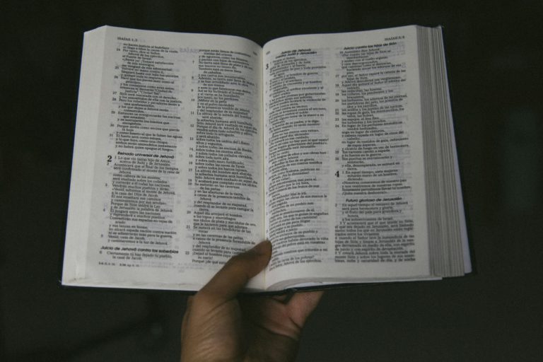 An open Bible in a hand lights the way to divine revelation.