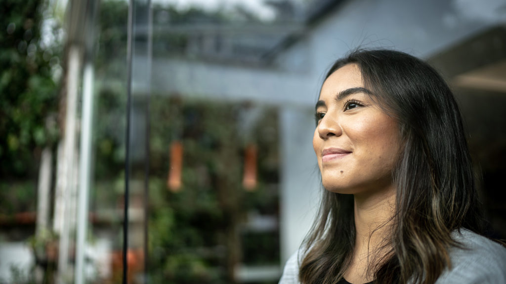 Royalty-Free Stock Photo: Young woman looking out a window while facing doubt.