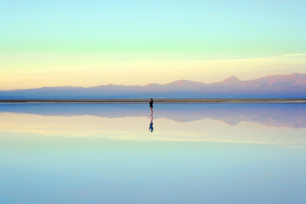 A woman stands in shallow water reflecting her image so that she can help you see yourself as God sees you.