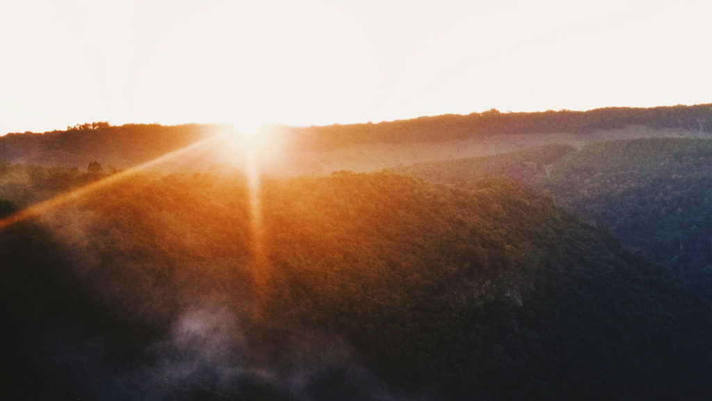 The rising sun peaks over a hill as God lets this little light shine.