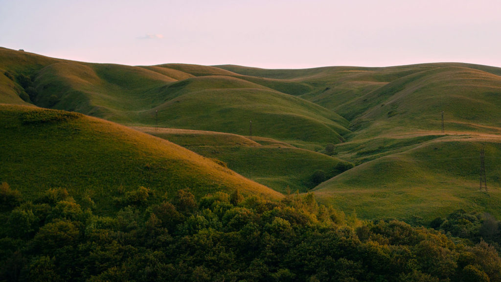 Rolling green hills with a light pink sky remind us to let God help us battle with anxiety.