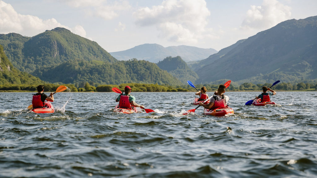 Friends kayak on a lake in the mountains as they enjoy fellowship.