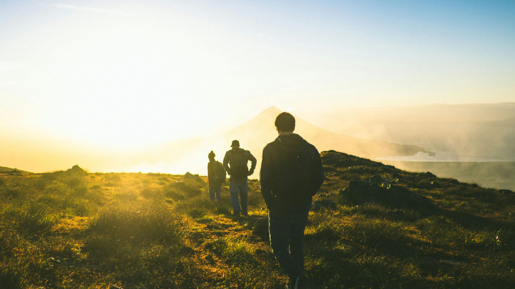 three friends walk on a path at sunset making sure love is the theme of their friendship.