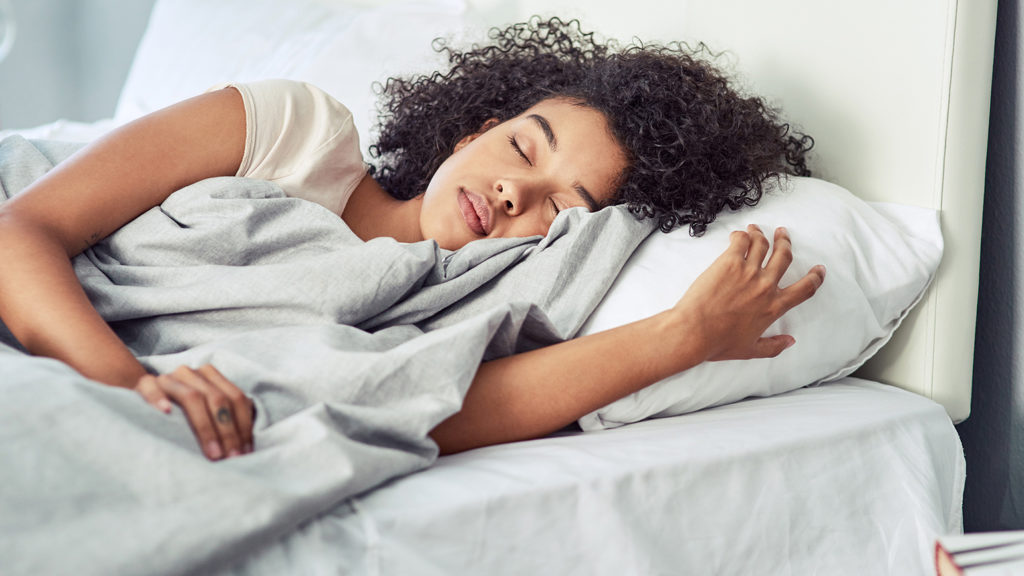 Woman sleeps peacefully in bed after doing her sleep tips