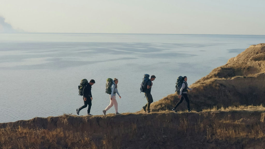 Friends hike together on a mountain path overlooking a valley filled with clouds as they find comfort in community.